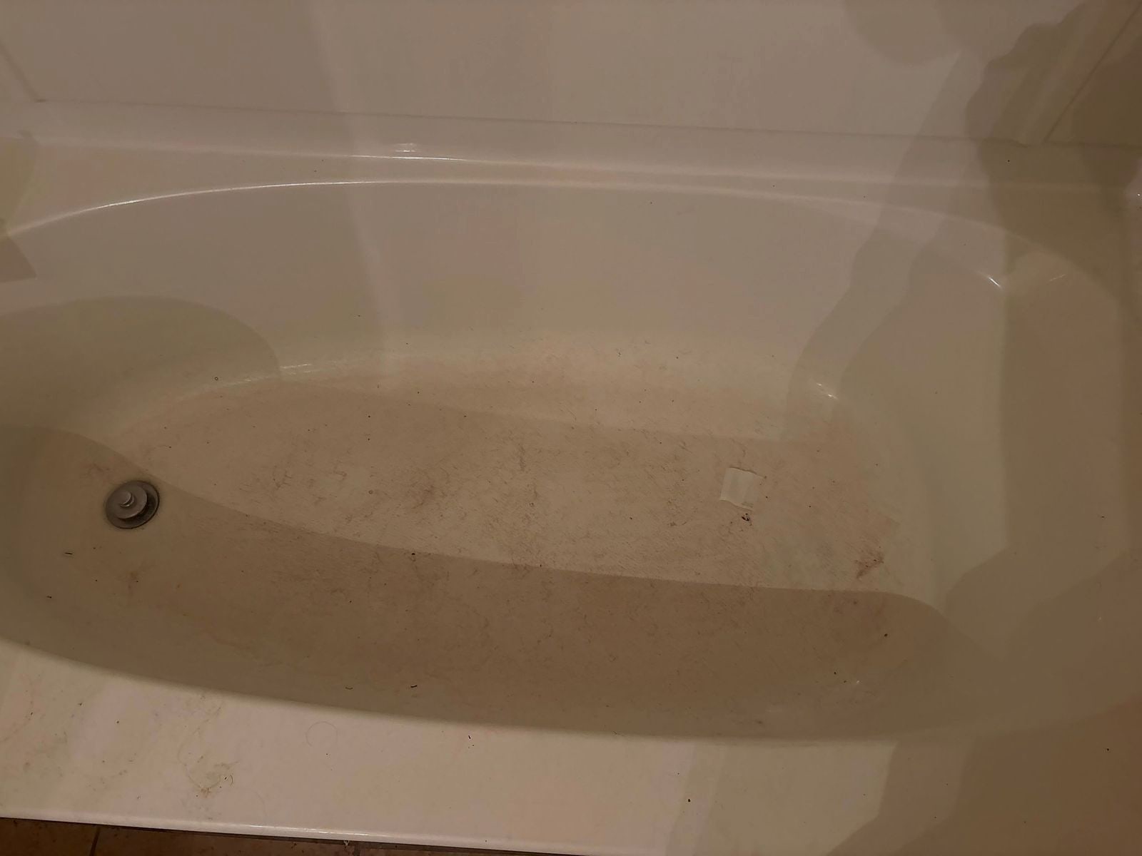 Bathtub basin with grime and soil before a vacation rental turnover