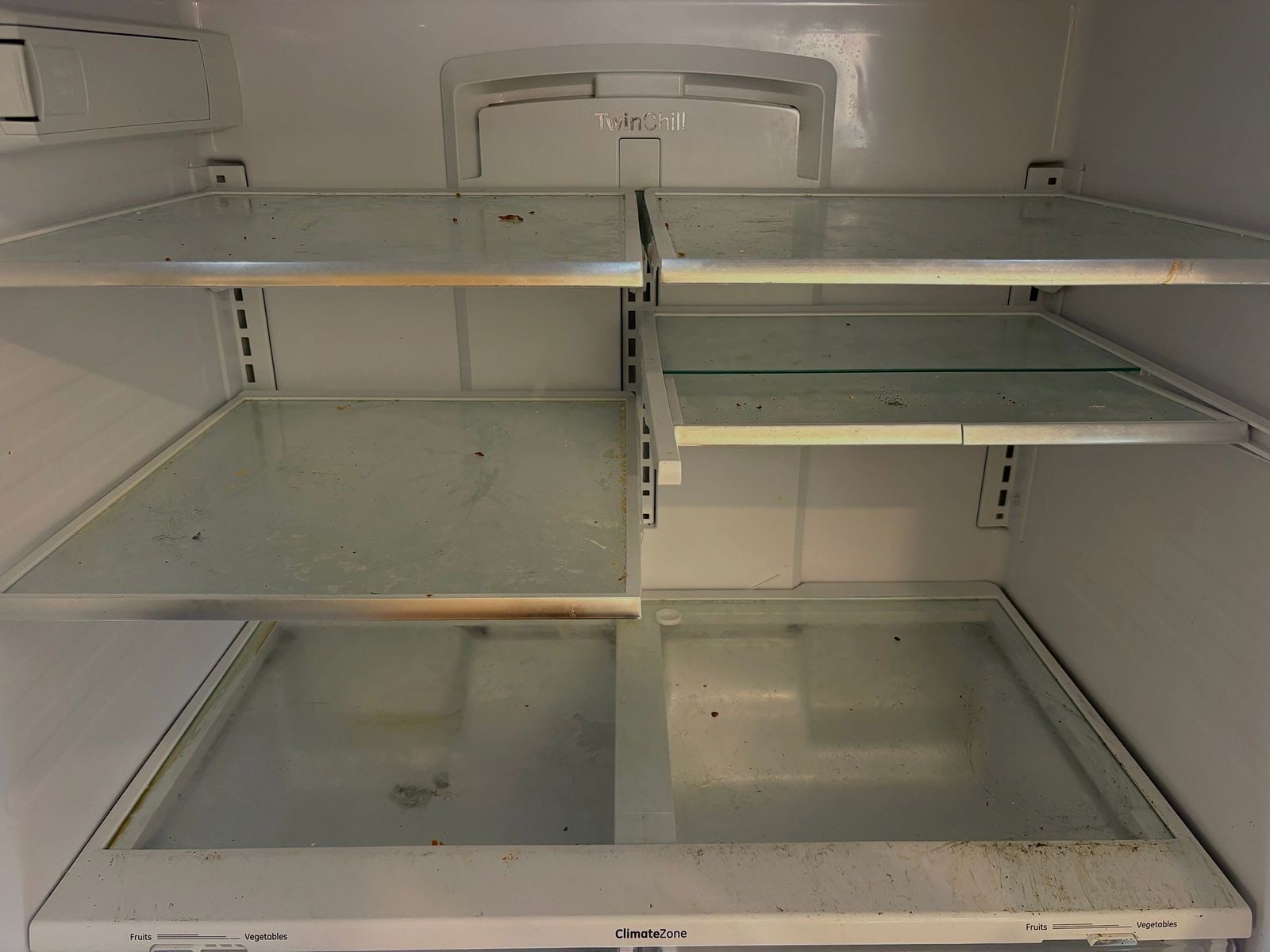 Refrigerator interior with spills and residue before a move-out clean
