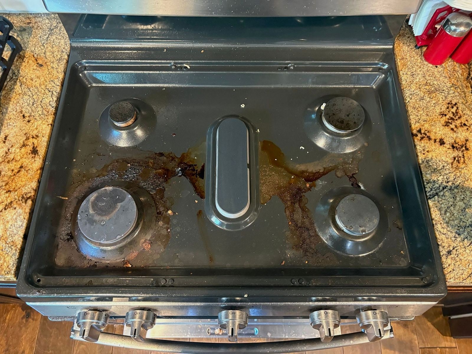 Stainless gas cooktop coated in burnt-on grease before a turnover clean