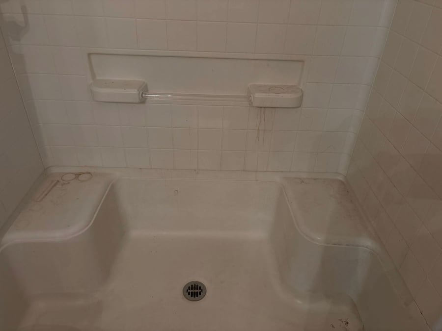 Shower seat with soap scum and staining before a deep clean