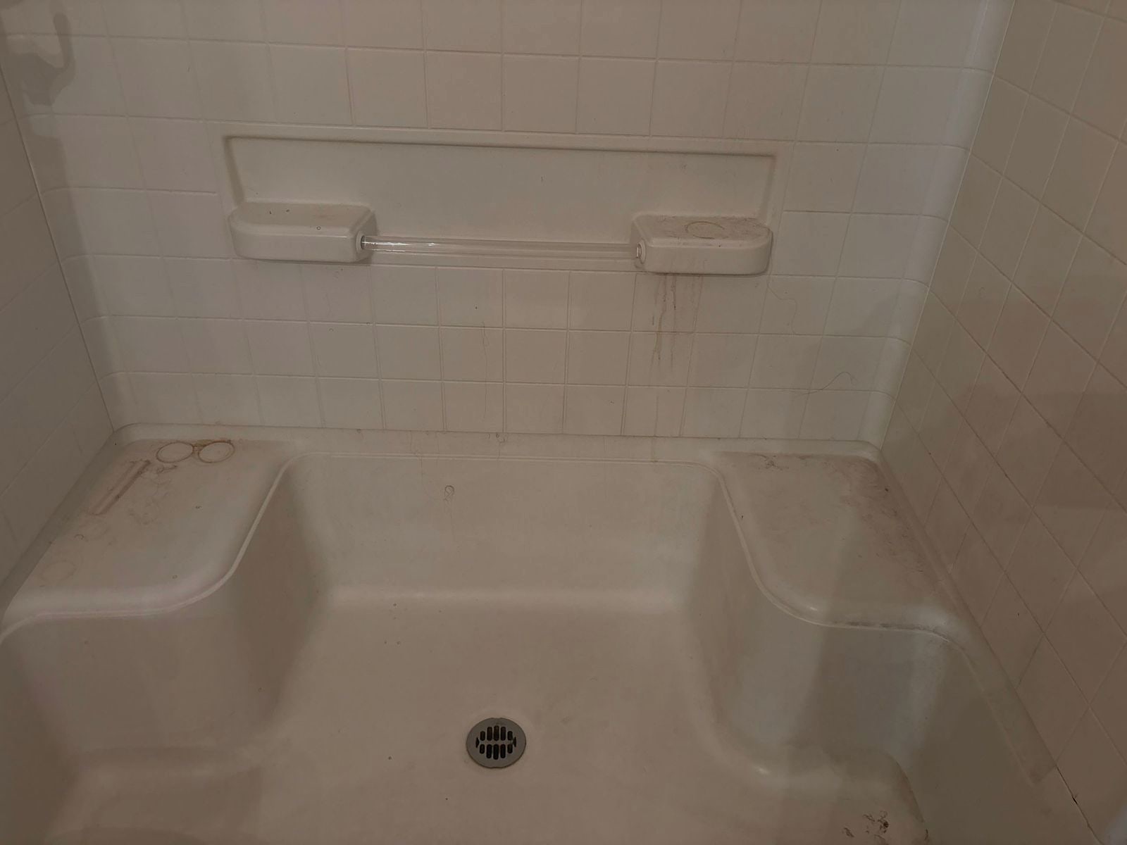 Shower stall and built-in seat with grime before a vacation rental turnover
