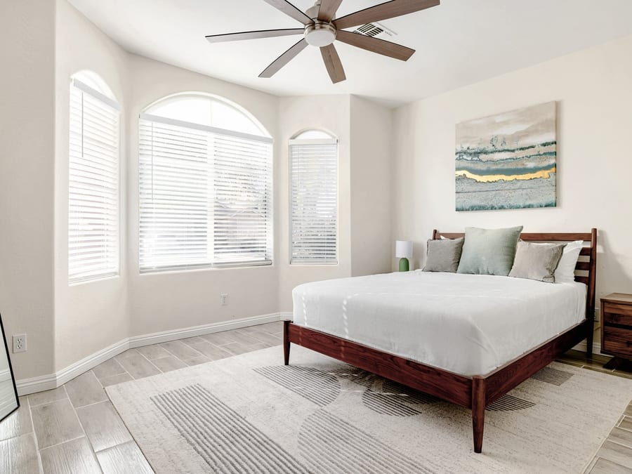 Bright, freshly cleaned bedroom with a made bed and arched windows